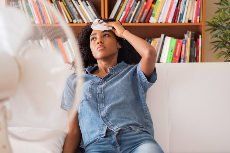 Woman sweating and trying to refresh at home.