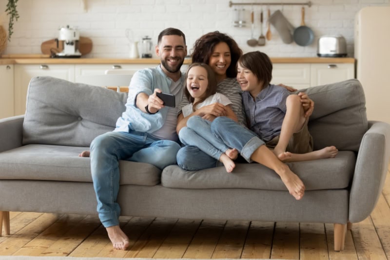 What Are the Signs that I Need a New Furnace? Photo of a family of four laughing and posing for a photo on a couch together.